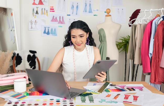 아름다운 아시아 패션 디자이너가 컴퓨터 노트북에 새 컬렉션을 그리기 위한 스케치