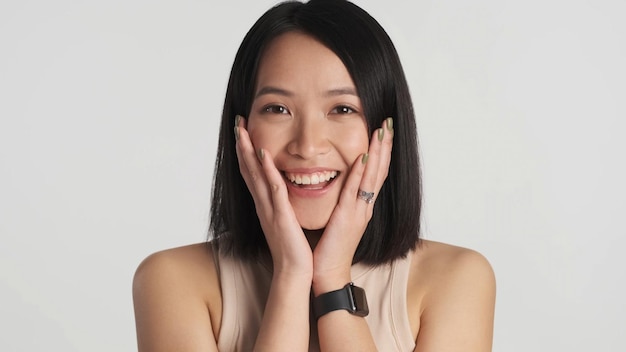 Beautiful Asian girl looking charming at camera over white background Wow expression