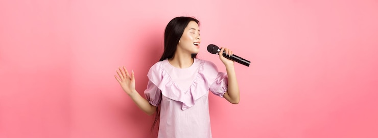 無料Photo 美しいアジアの女の子がマイクで歌を歌い、再びドレスを着てロマンチックな笑顔を見せる