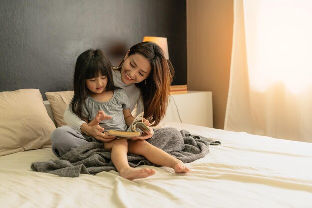 かわいい娘の幸せの瞬間を持つ美しいアジアのシングルママは宿題を教える宿題のアイデアコンセプト家の背景