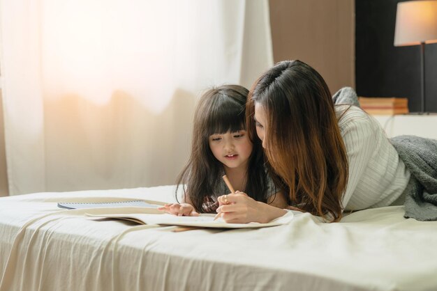 Beautiful asian single mom with cute daughter happiness moment time teach homework homeschool ideas concept house background