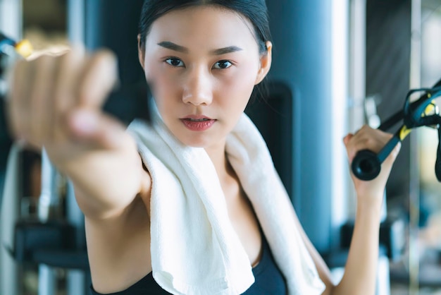 フィットネスで運動するウエイトマシンで美しいアジアのスポーツ女性のトレーニング美しい女性は、フィットネススポーツコンセプトboduビルダー健康的なライフスタイルのトレーニング中に重いダンベルを持ち上げます