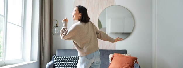 Free Photo beautiful asian woman dancing feeling happy and upbeat singing into hand microphone express joy