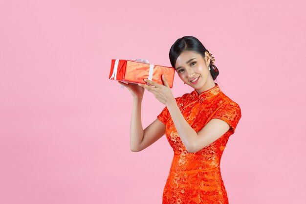 Beautiful asian woman happy smile and holding gift box in chinese new year on pink background