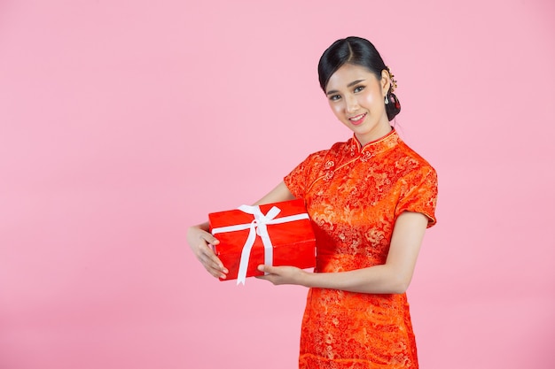 아름 다운 아시아 여자 행복 한 미소와 분홍색 배경에 중국 새 해에 선물 상자를 들고.