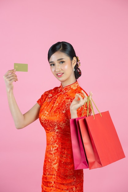美しいアジアの女性の幸せな笑顔とピンクの背景に中国の旧正月のショッピング。
