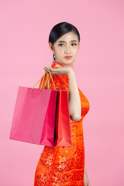 Beautiful Asian woman happy smile and shopping in chinese new year on pink background.