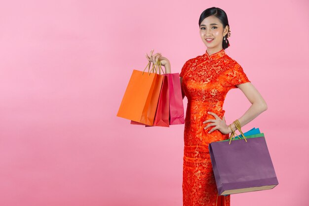 아름 다운 아시아 여자 행복 한 미소와 분홍색 배경에 중국 새 해에 쇼핑.
