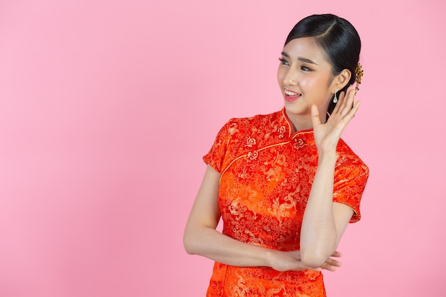 ピンクの背景に中国の旧正月に、美しいアジア人女性の幸せな笑顔と口を大きく開いて叫ぶ。