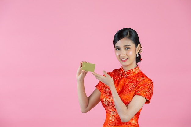 Улыбка красивой азиатской женщины счастливая и показать кредитную карту в китайском Новом году на розовом фоне.