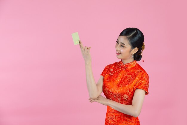 Beautiful Asian woman happy smile and show credit card in chinese new year on pink background.