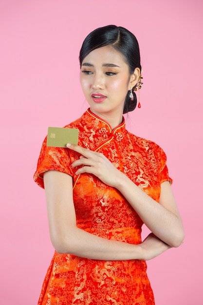 美しいアジア女性の幸せな笑顔とピンクの背景に中国の旧正月にクレジット カードを表示します。