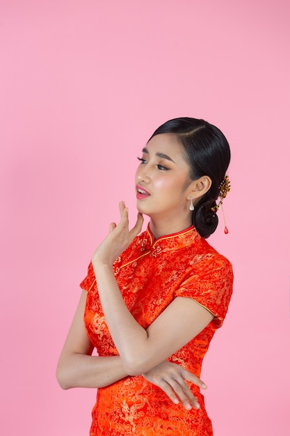 Beautiful Asian woman happy smile and show something to you in chinese new year on pink background.