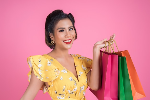 色の買い物袋を保持している美しいアジアの女性