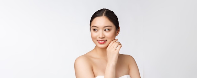 흰색 배경에 격리된 웰빙으로 완벽한 미인의 뺨과 미소 얼굴을 만지는 화장품 소녀의 아름다운 아시아 여성 화장