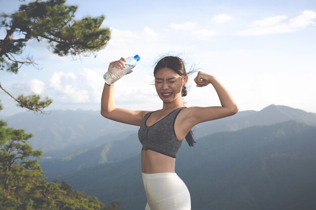 A beautiful Asian woman meditating and exercising on the top of the mountain.