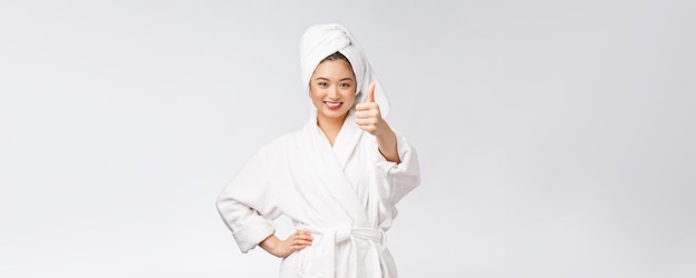 Красивая азиатская женщина с идеальной кожей показывает большие пальцы на белом фоне