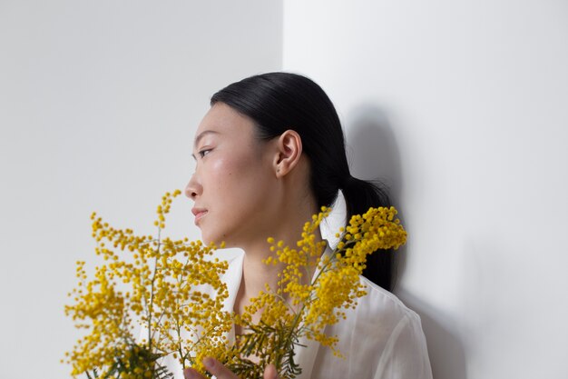 Beautiful asian woman posing holding yellow flowers with perfect skin