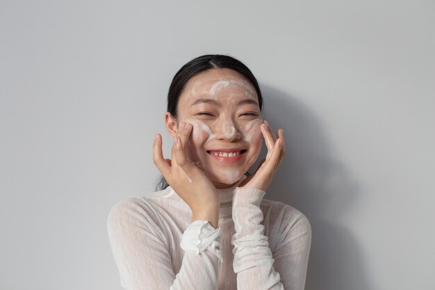 Beautiful asian woman posing with facial cream