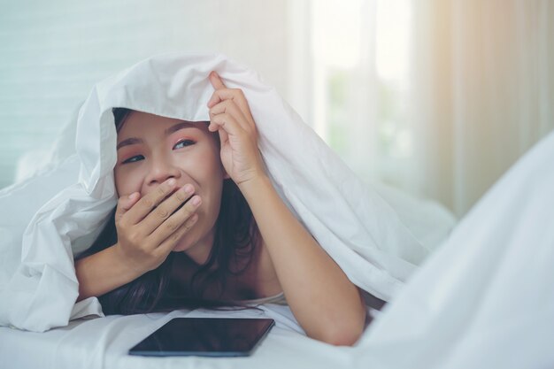 A beautiful Asian woman relaxes and works with a laptop computer, reading at home.