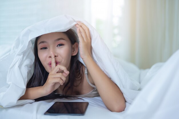 A beautiful Asian woman relaxes and works with a laptop computer, reading at home.