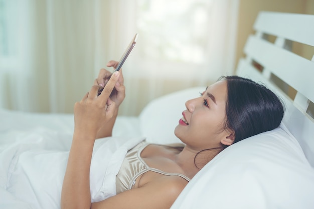 A beautiful Asian woman relaxes and works with a laptop computer, reading at home.