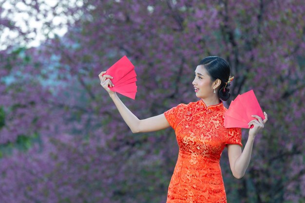 Красивая азиатская женщина что-то показывает и берет красные конверты в китайском новом году
