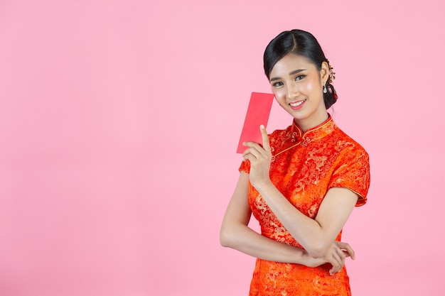 美しいアジアの女性が何かを見せ、中国の旧正月に赤い封筒を取る