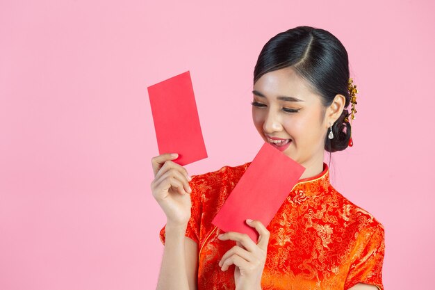 美しいアジアの女性が何かを見せ、中国の旧正月に赤い封筒を取る