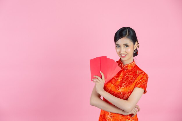 아름다운 아시아 여자가 뭔가를 보여주고 중국 새해에 빨간 봉투를 가져 가라.