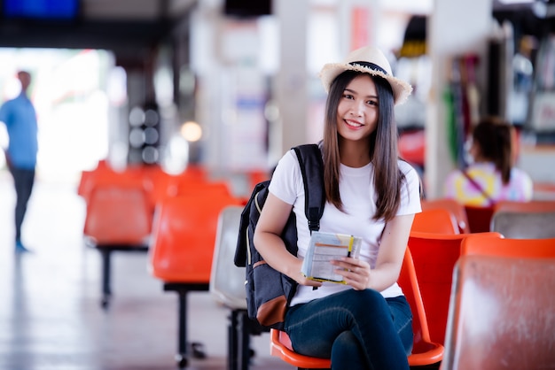 Beautiful Asian woman  smiling with map and bag at bus station