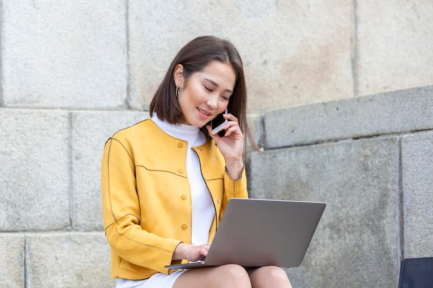 Beautiful asian woman using laptop computer Smiling asian girl sitting on stairs and using a laptop Asian business woman using laptop computer