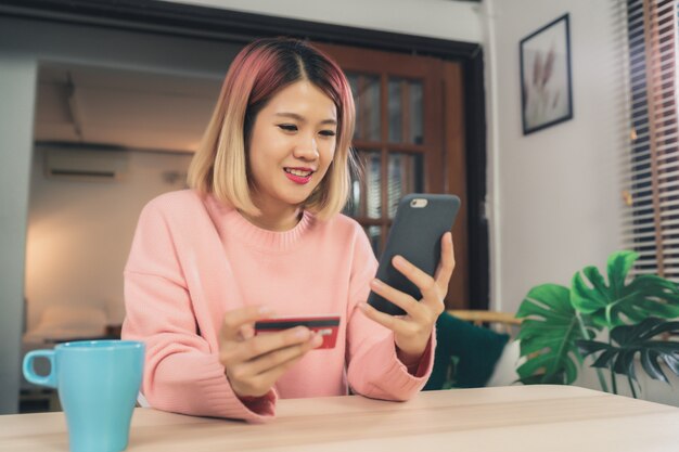 Красивая женщина Азии, используя смартфон, покупая онлайн-покупки с помощью кредитной карты