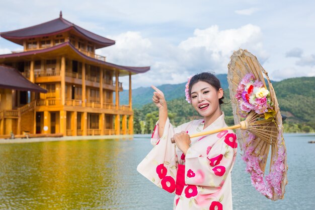 Красивая азиатская женщина нося японское кимоно, традиционную концепцию платья.