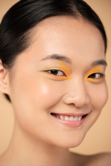 Красивая азиатская женщина, носящая оранжевые тени для век