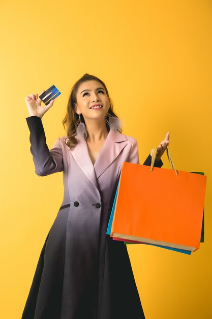 Красивая азиатская женщина с хозяйственной сумкой и кредитной карточкой в руке