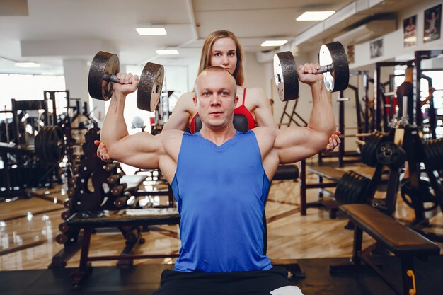 A beautiful and athletic sportswear girl training in the gym with friend