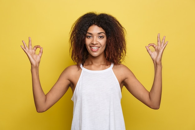 Free photo beautiful attractive african american woman with trendy glasses posting over yellow studio background. copy space.