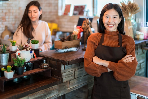 無料写真 美しい魅力的なアジアのカフェショップのオーナーは、コーヒーカップエプロンカフェの背景と幸せと喜びで笑顔