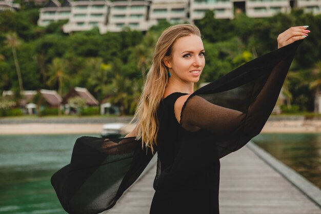 럭셔리 리조트 호텔, 여름 휴가, 열대 해변에서 부두에 포즈 검은 드레스를 입은 아름다운 매력적인 여자