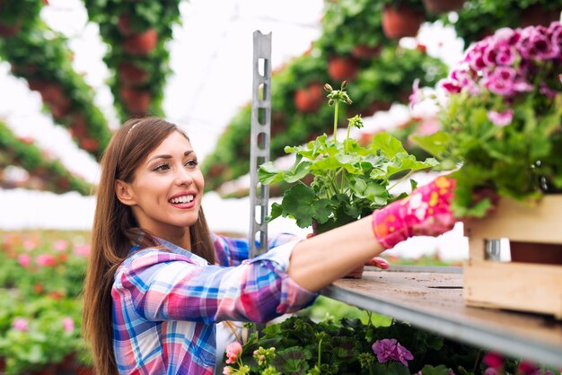 온실 정원에서 꽃을 돌보는 아름 다운 매력적인 여자 꽃집