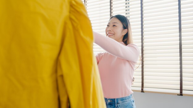 집이나 상점에서 옷장에 그녀의 패션 복장 옷을 선택하는 아름 다운 매력적인 젊은 아시아 아가씨.