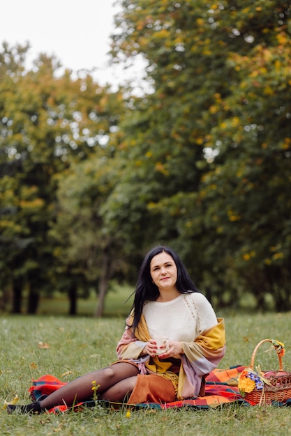 美しい秋の少女の肖像画。秋の公園で黄色の葉の上にポーズをとる若い女性。アウトドア