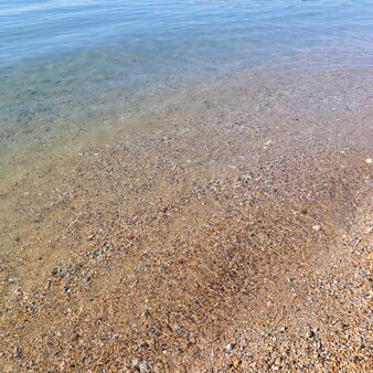 Beautiful background of blue calm sea with little fish sand and pebbles rest and relaxation on