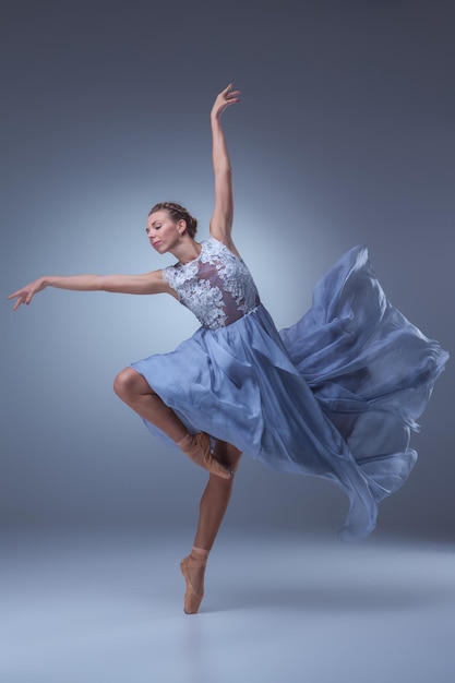 Красивая балерина танцует в синем длинном платье
