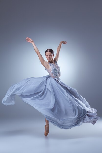 The beautiful ballerina dancing in long lilac dress on lilac background