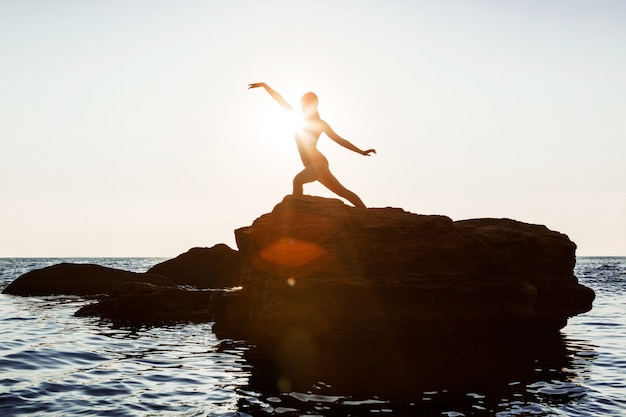 Beautiful ballerina dancing, posing on rock at beach, sea views.