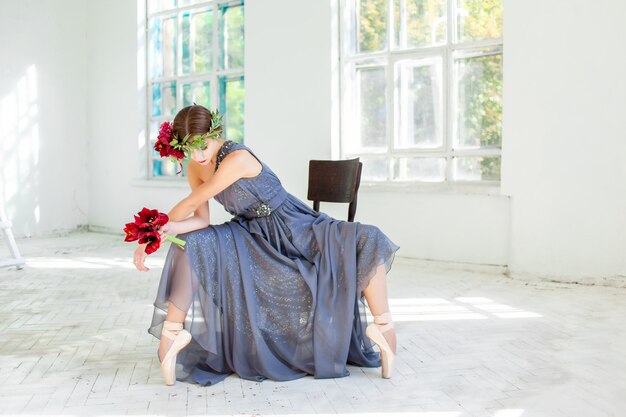 красивая балерина сидит в длинном сером платье