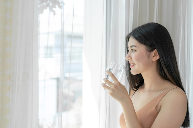 아름다운 아름다움 여자 아시아 귀여운 소녀는 아침에 건강을 위해 깨끗한 마시는 물을 마시는 행복한 느낌