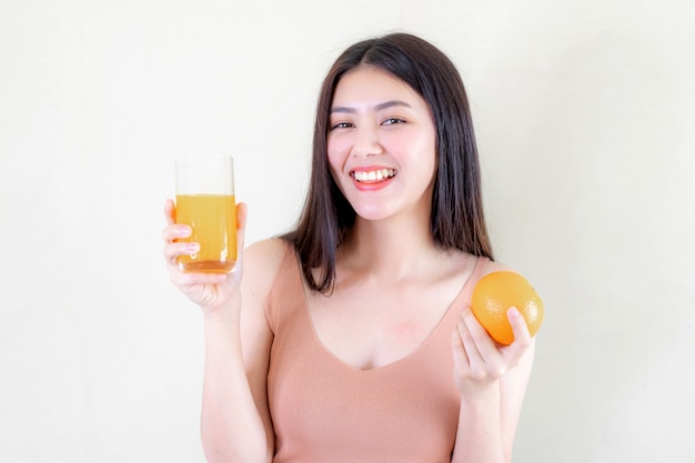 美しい美しさの女性アジアのかわいい女の子は午前中に健康のためにオレンジジュースを飲んで幸せを感じる